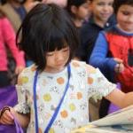 Student selects book from a table of books during a reading event.